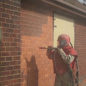 View Worker blast cleaning brick building
